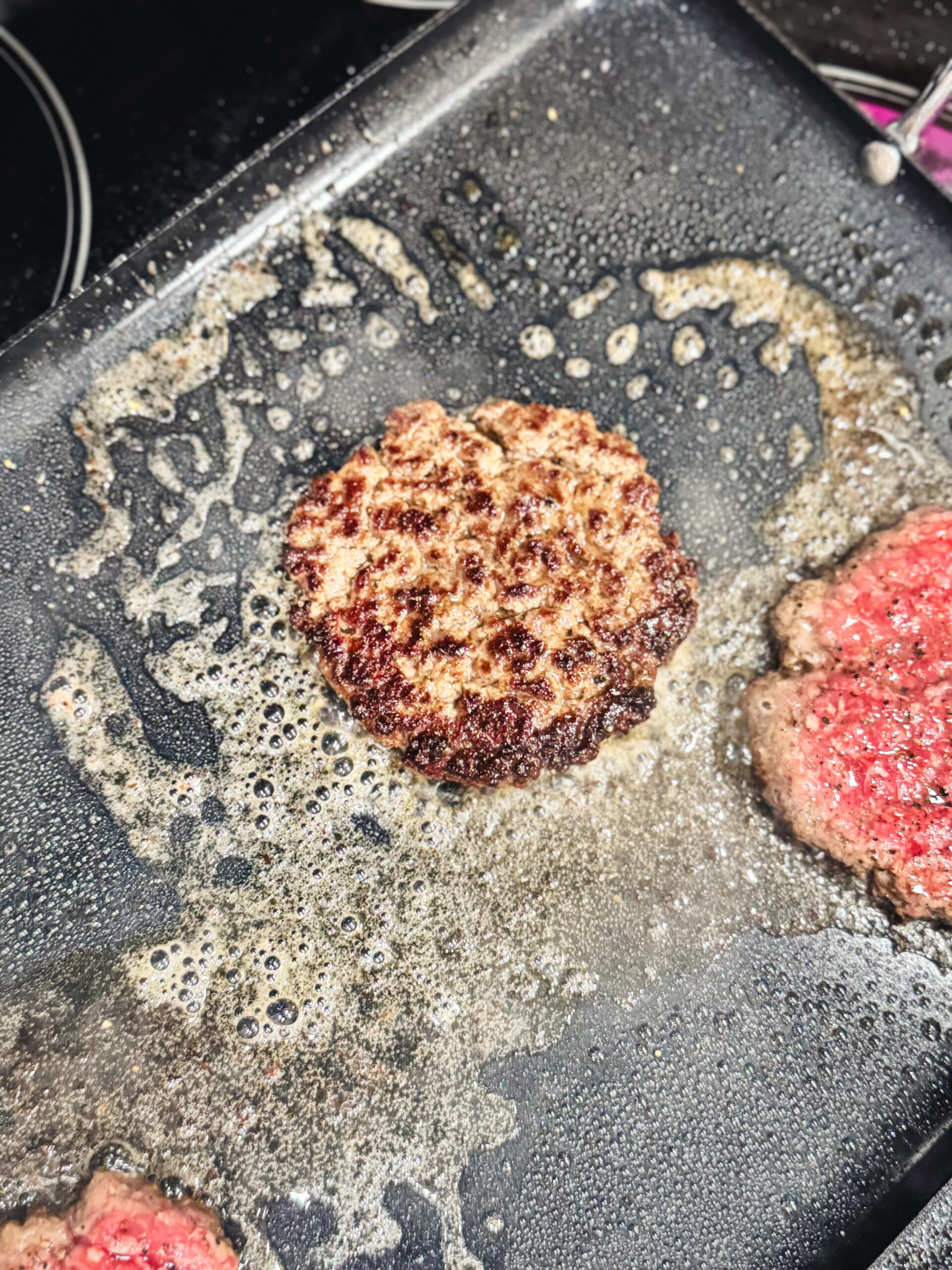 Sizzling smash burger on a griddle.