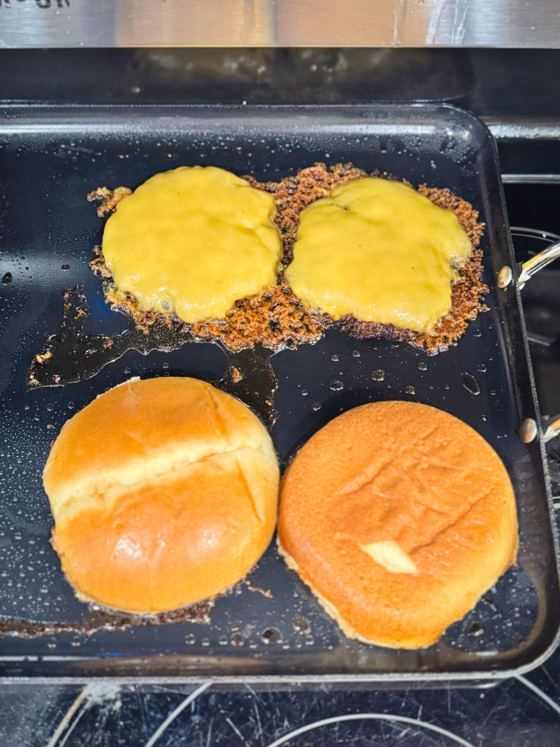 Melting cheese and toasting buns for smash burgers.