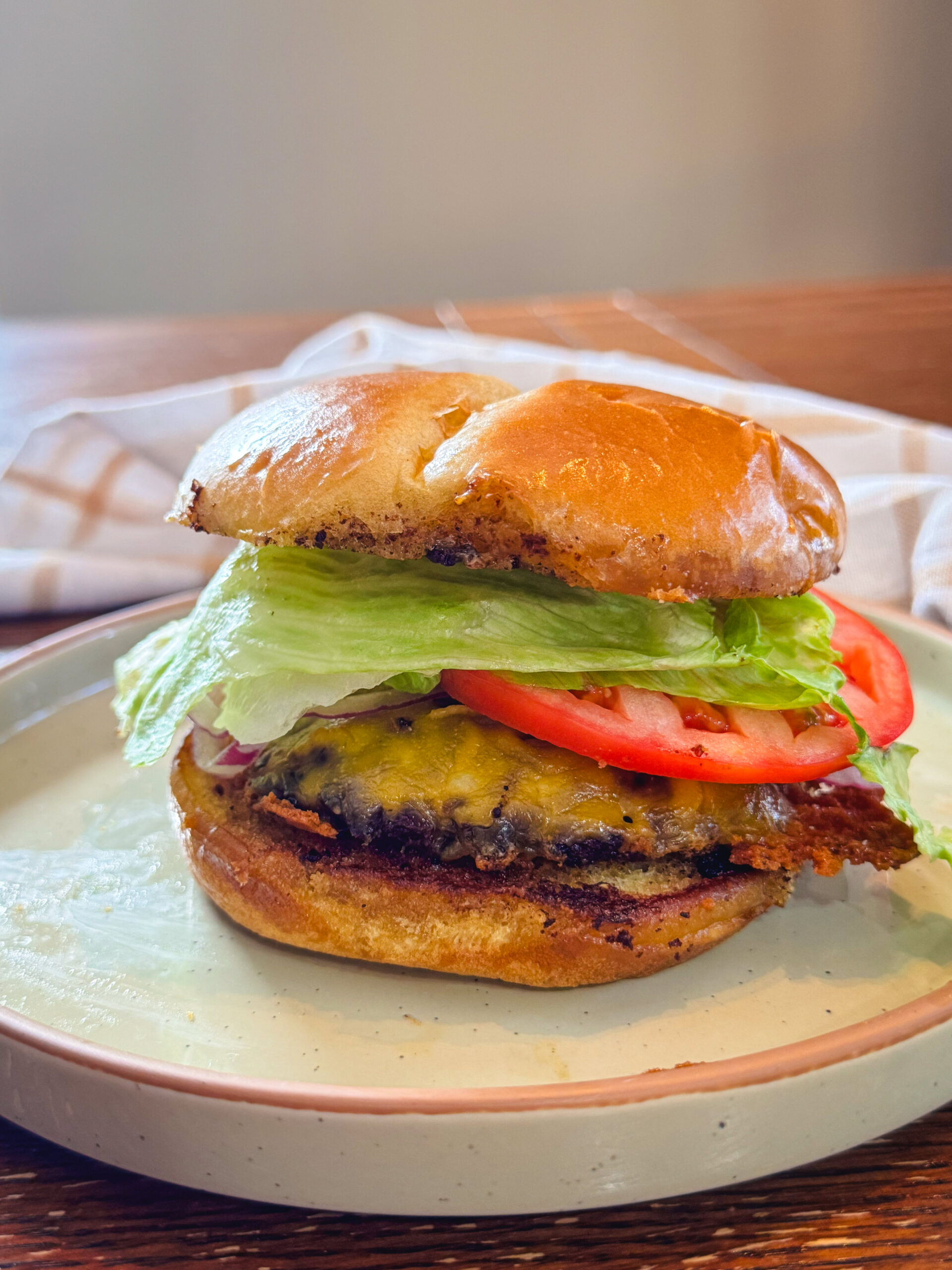 A stacked smash burger with lettuce, tomato, and cheese.