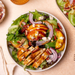 A serving of grilled chicken and peach salad in a white bowl.