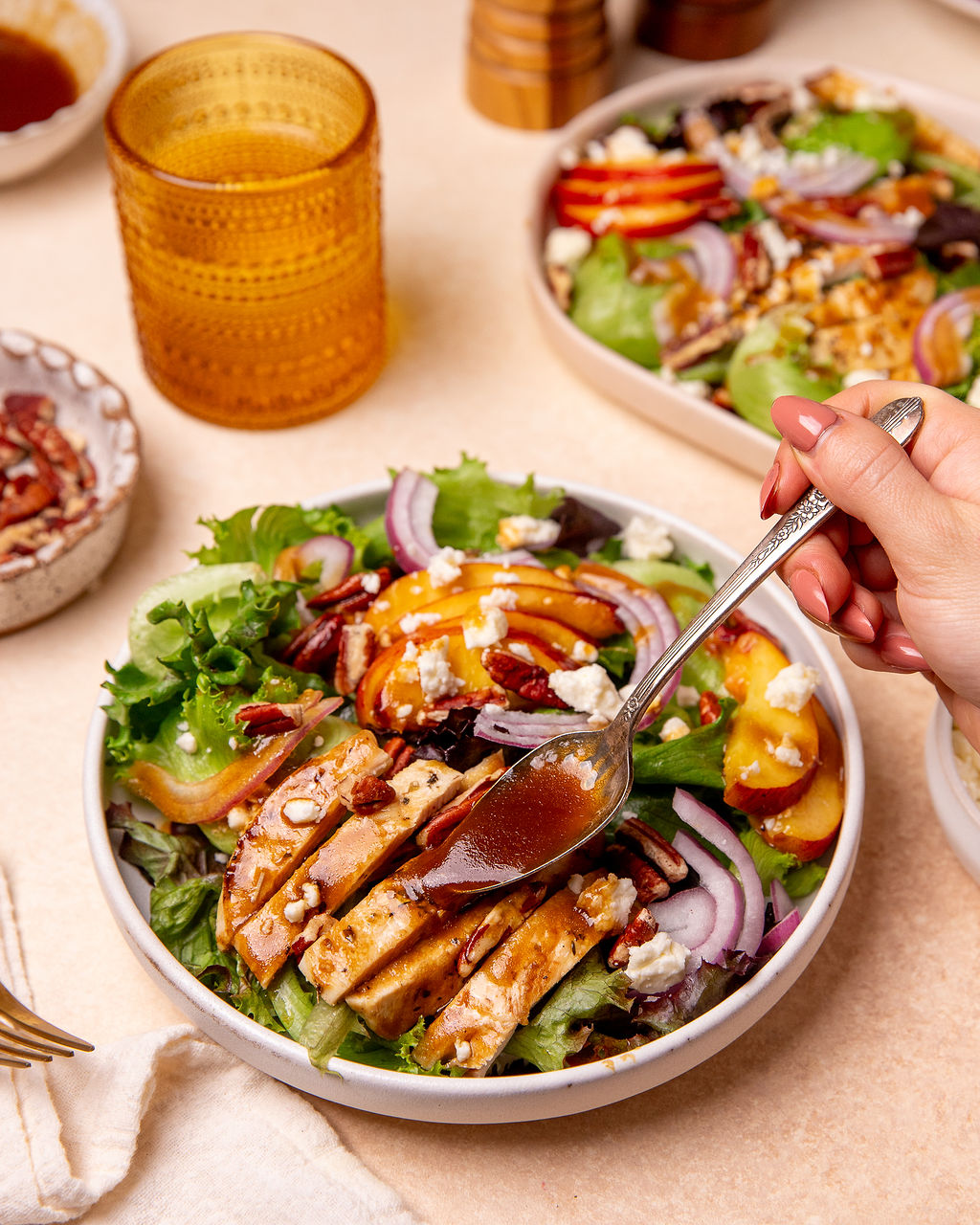 Adding balsamic dressing to grilled chicken and peach salad.