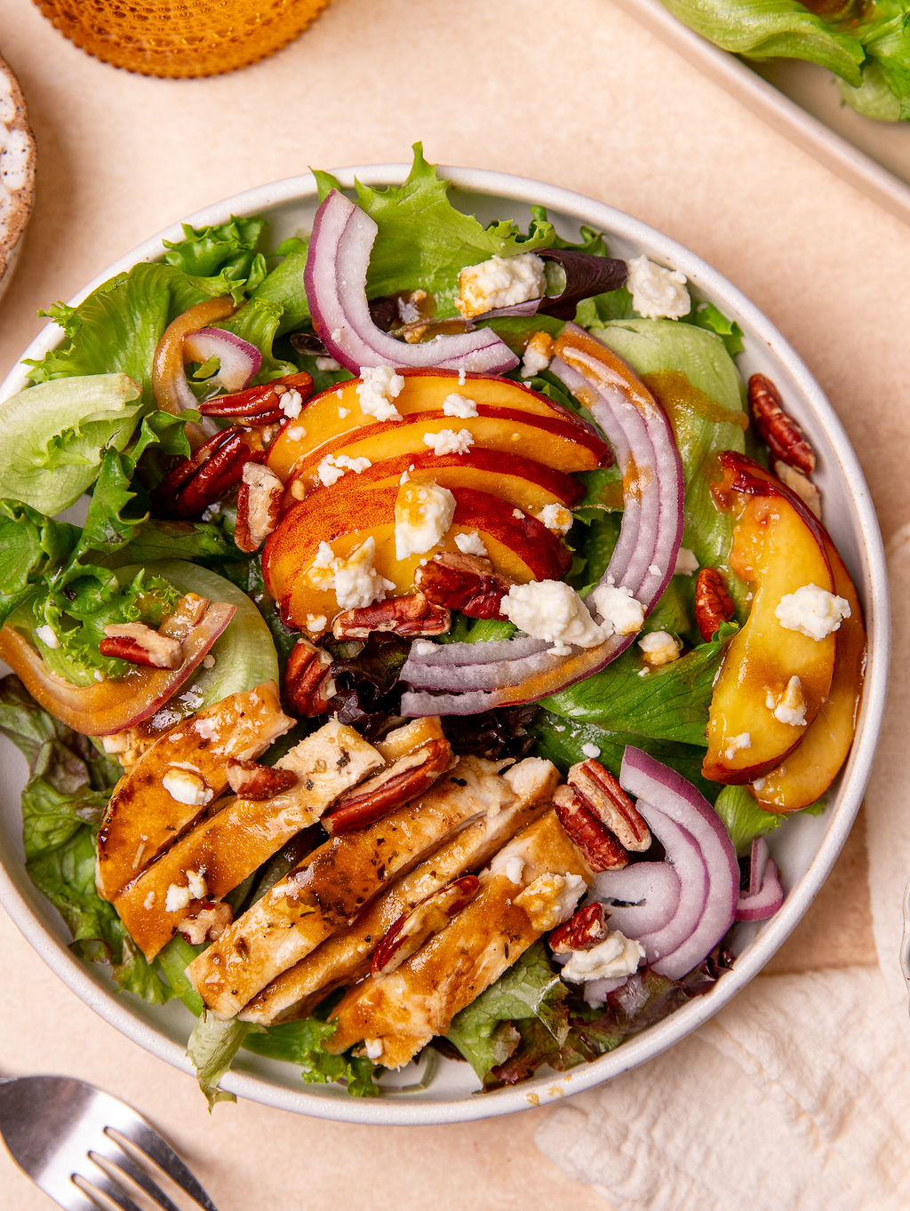 Delicious grilled peach and chicken salad in a white bowl.