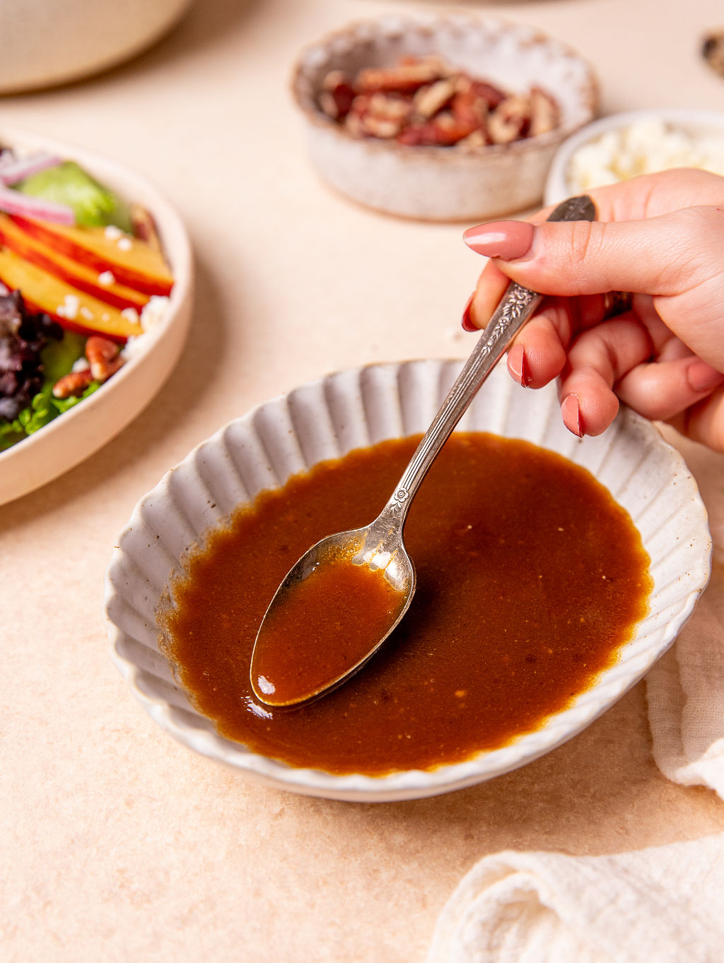 Tangy balsamic dressing in a white dish with a spoon dipped in.