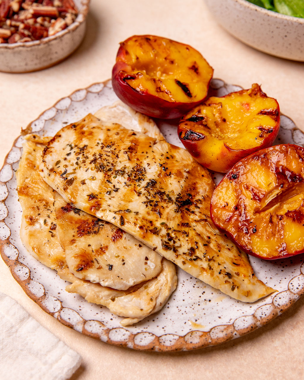 Grilled chicken and grilled peaches on a plate.