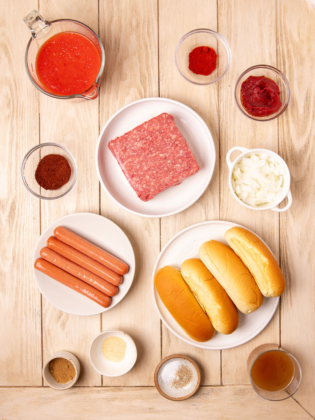 Ingredients for chili dogs on a light wooden surface.