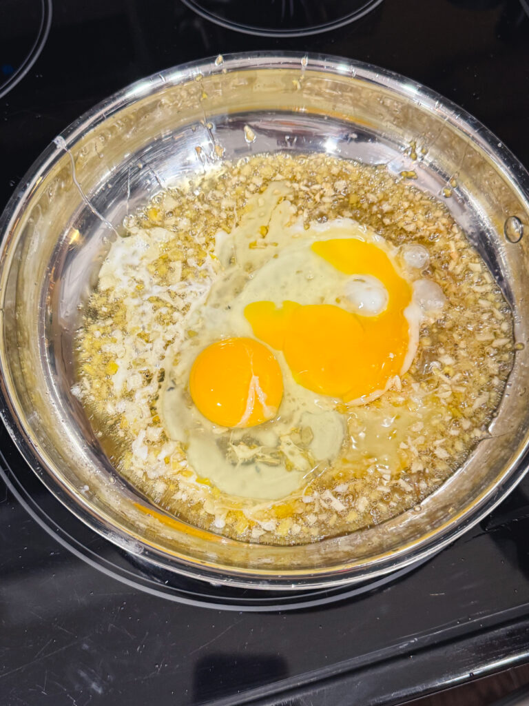 Cooking an egg in a skillet with garlic and ginger.