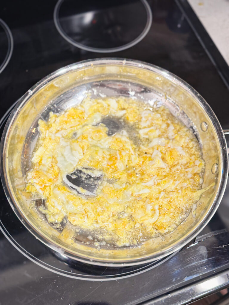 Sauteed garlic and ginger with scrambled eggs in a skillet.