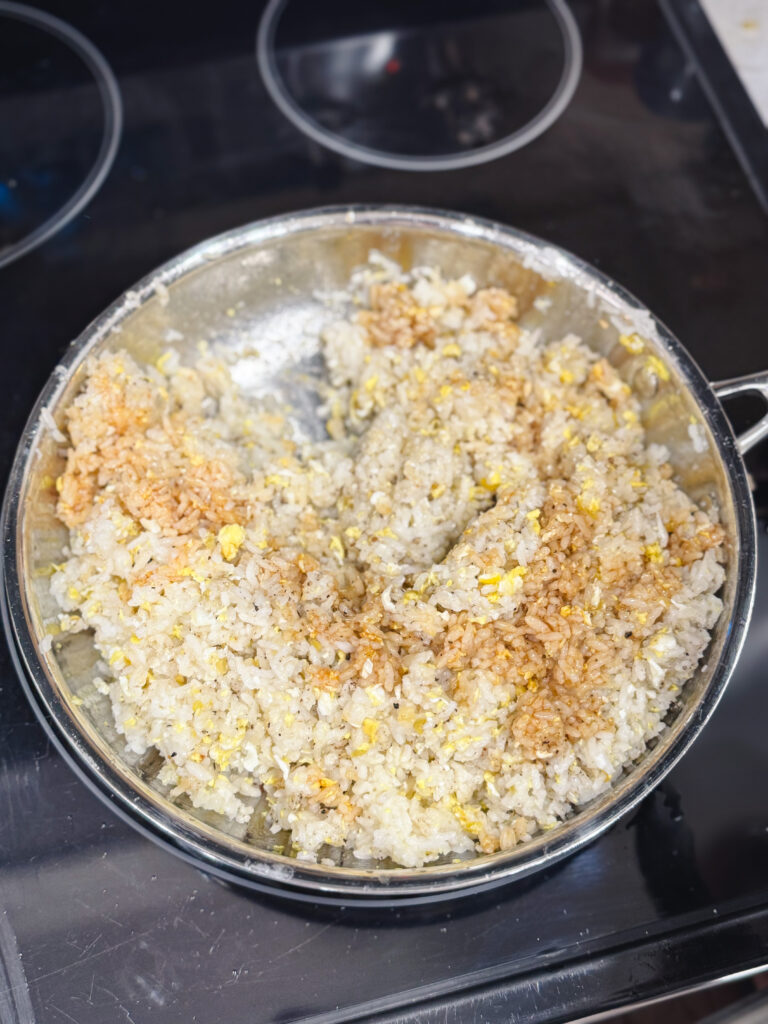 Adding soy sauce to a skillet of fried rice.