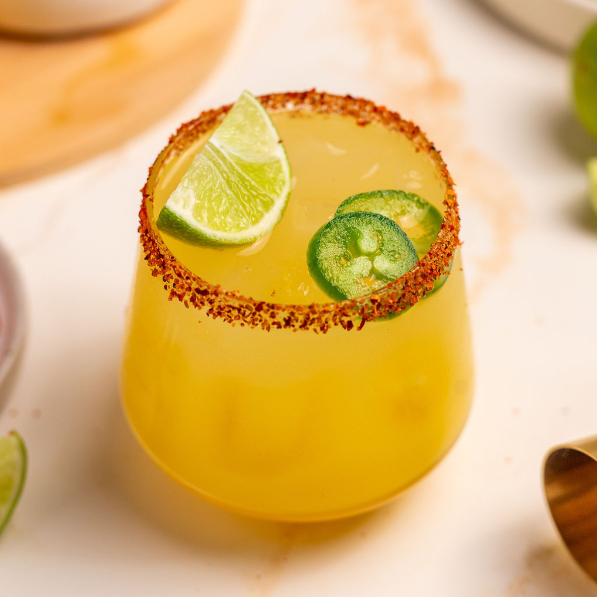 Spicy mockarita in a glass with Tajin on the rim and lime and jalapeno as garnish.