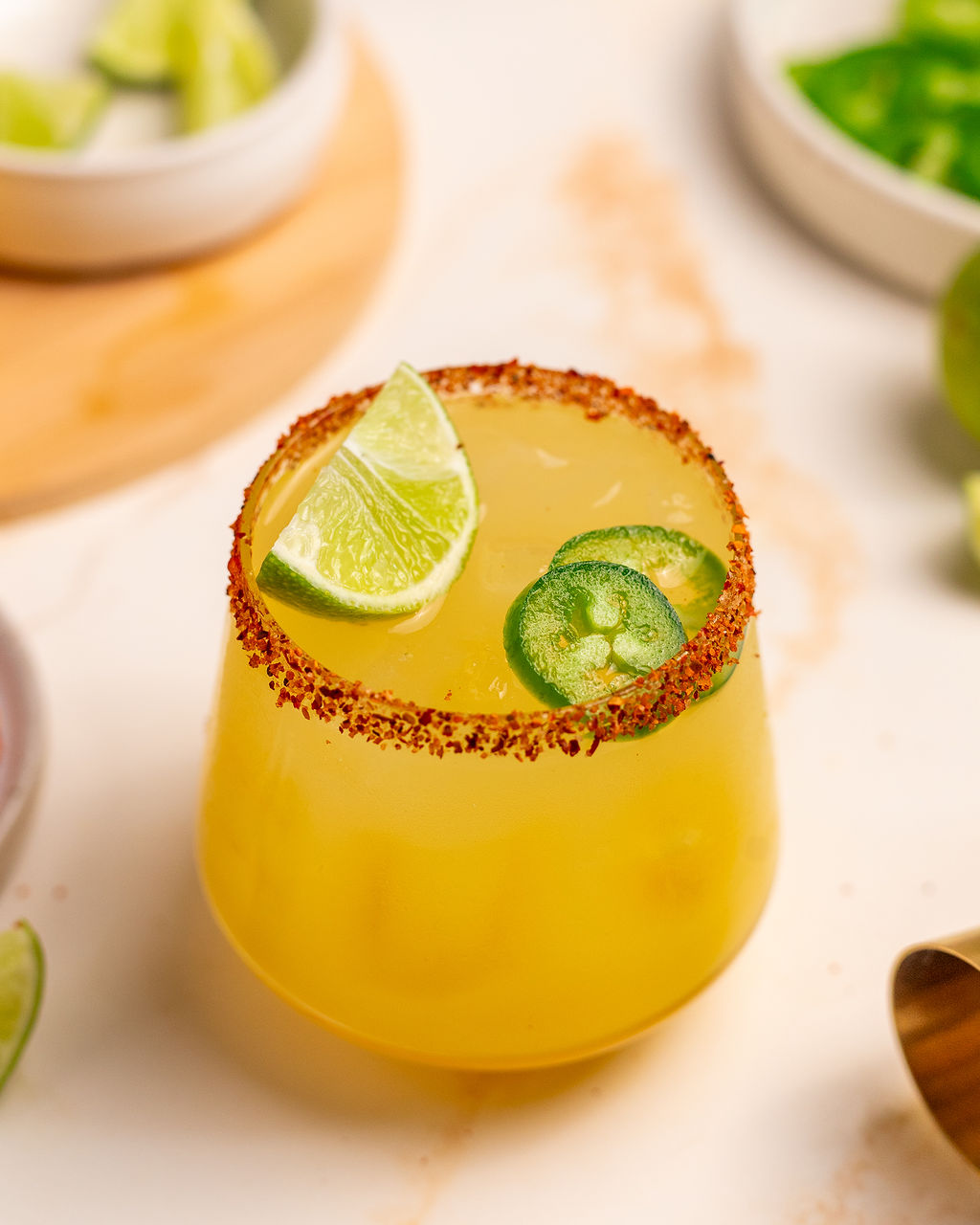 Spicy mockarita in a glass with Tajin on the rim and lime and jalapeno as garnish.
