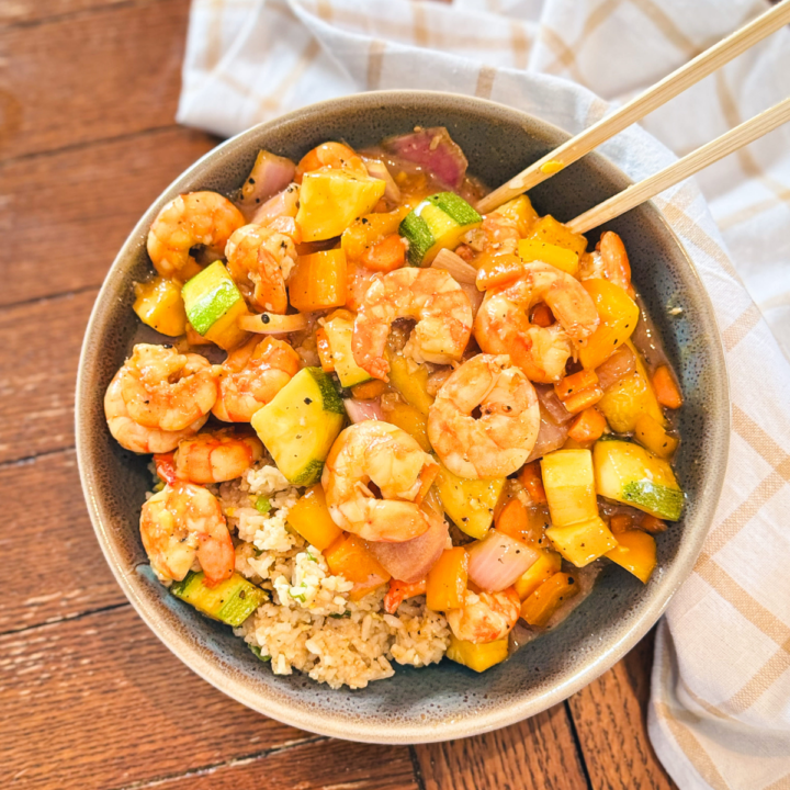 Sheet pan teriyaki shrimp in a bowl with chopsticks.