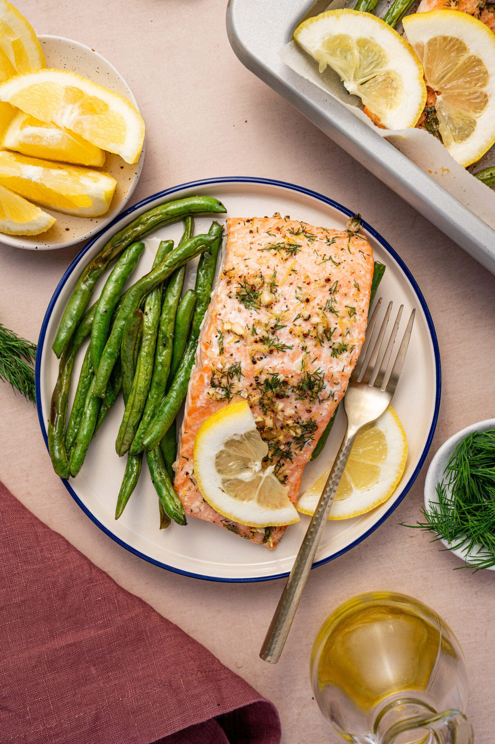 Lemon dill salmon with green beans and a slice of lemon.