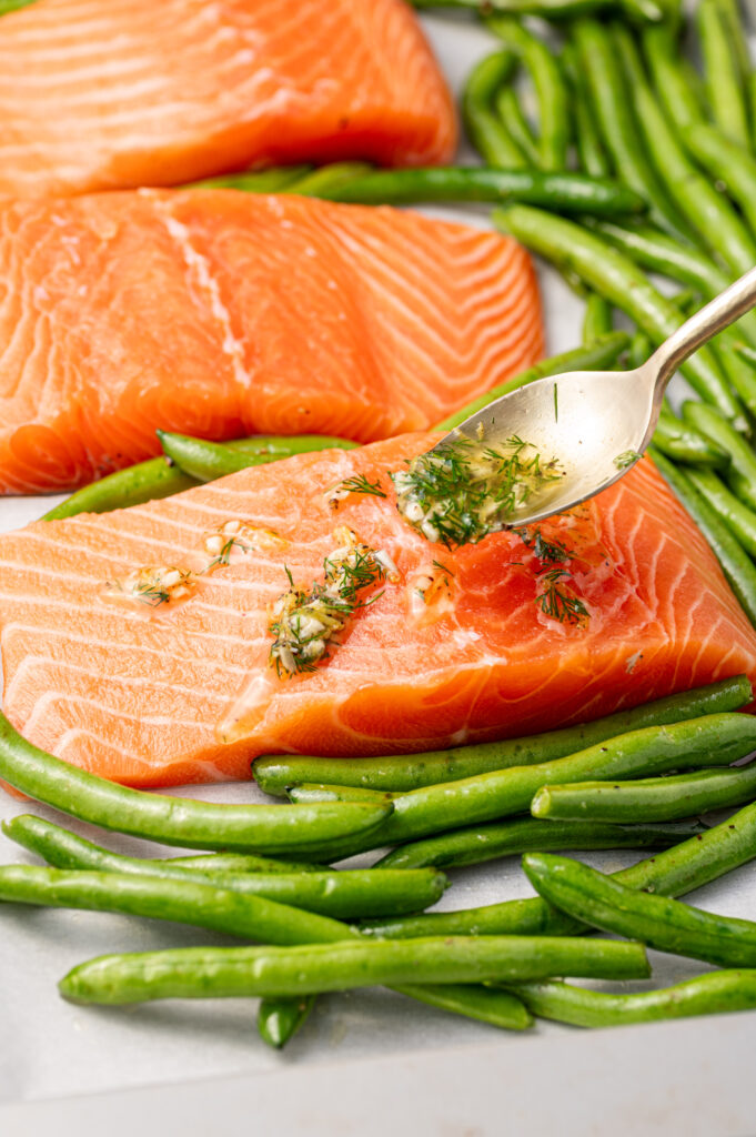 Spooning the lemon dill sauce on salmon fillets.