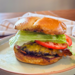 A stacked smash burger with lettuce, tomato, and cheese.