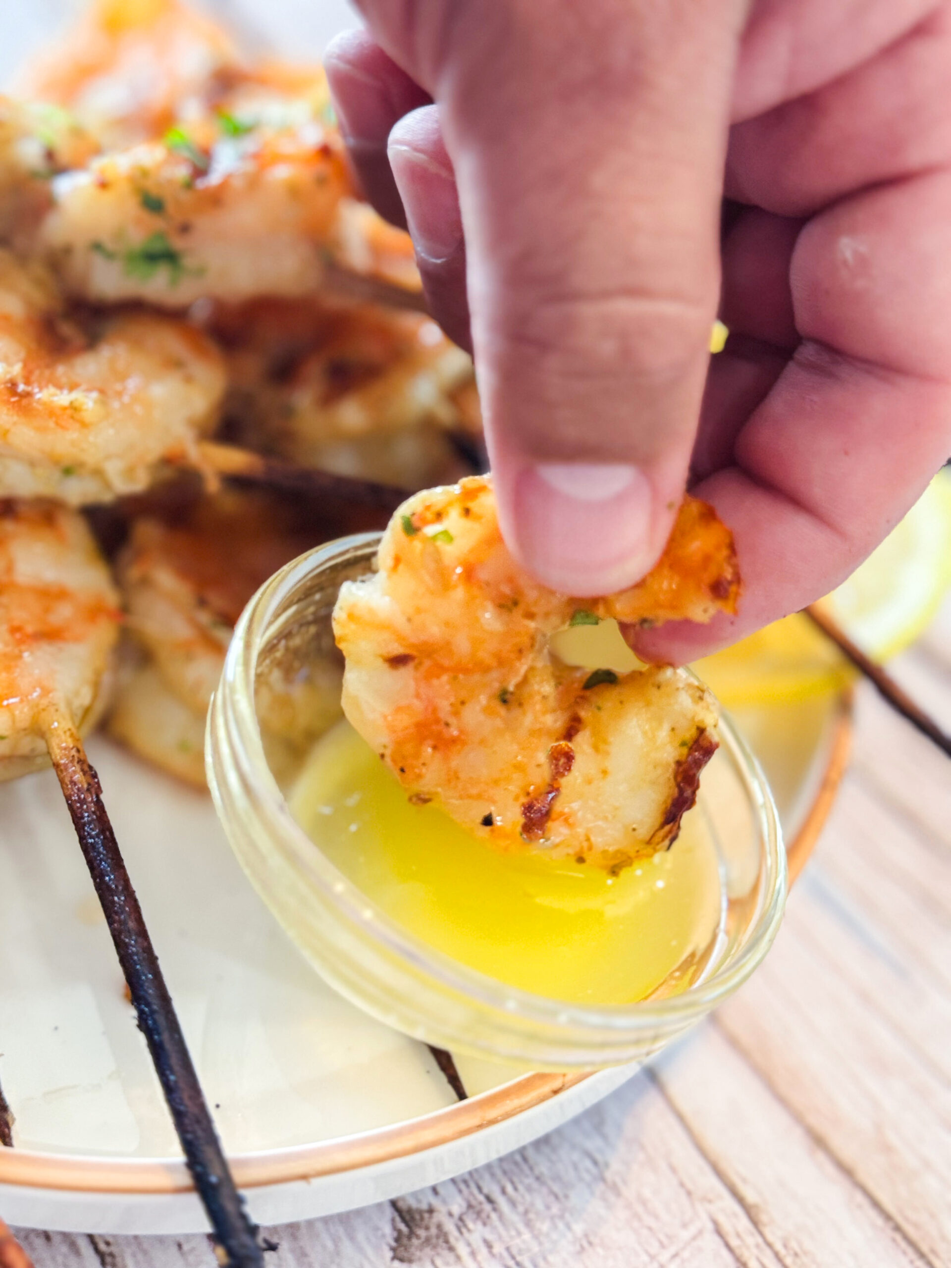 Dipping grilled shrimp in garlic butter.