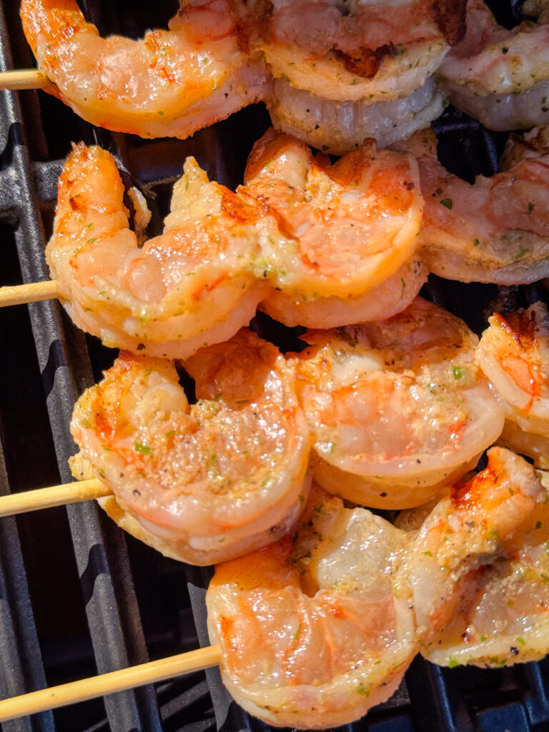 Skewered shrimp turning pink on the grill.