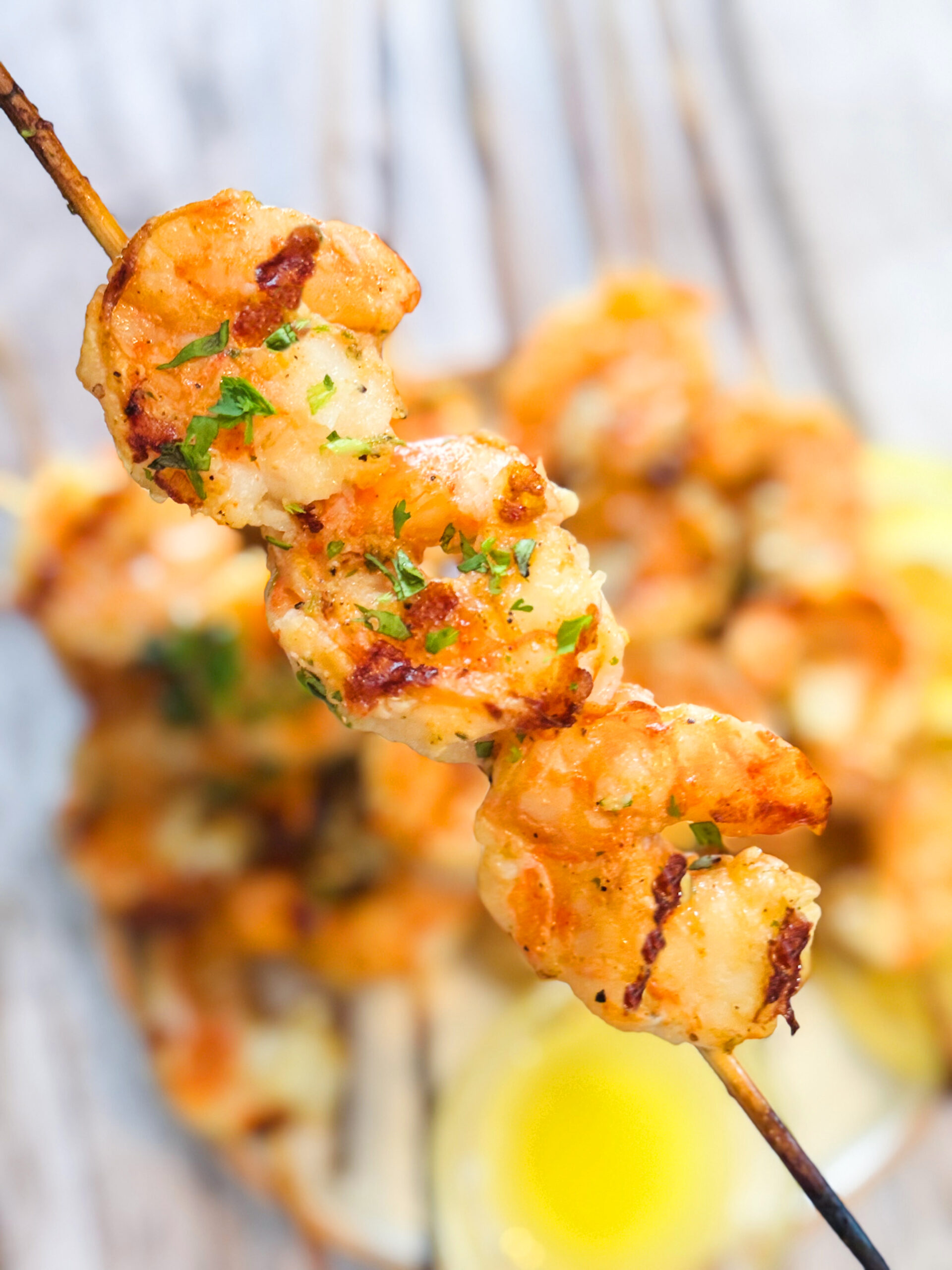 A skewer of grilled shrimp with grill marks and parsley as a garnish.