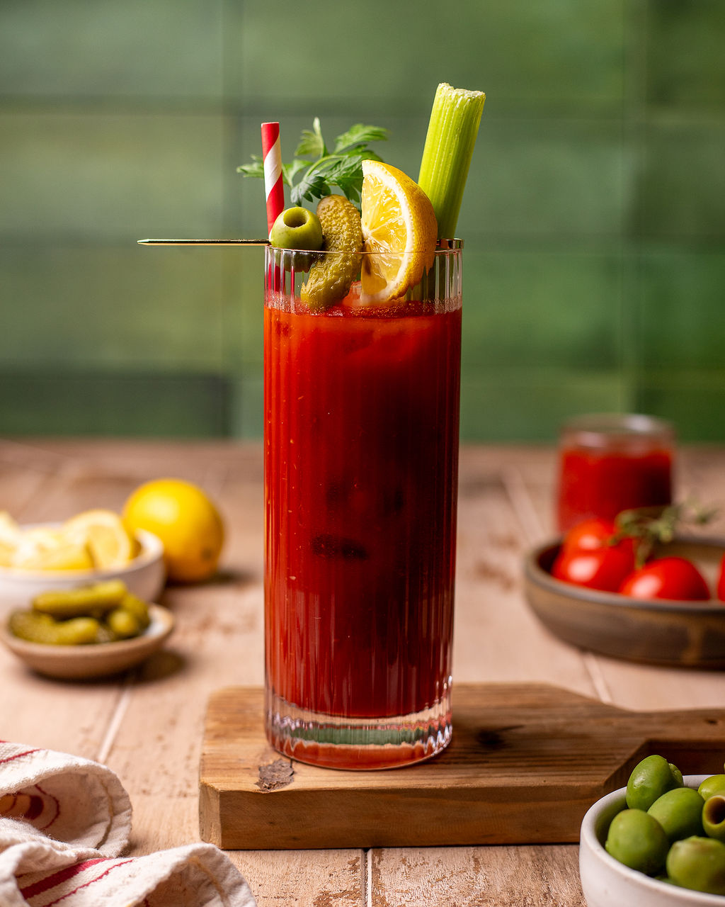 Blood Mary mocktail with pickles, sliced lemon, celery, and parsley as a garnish.