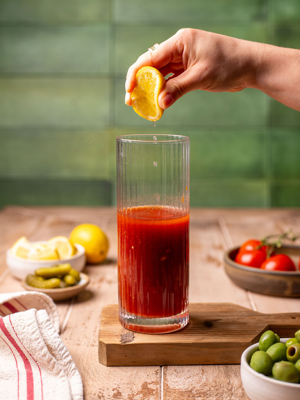 Squeezing lemon juice into a glass of tomato juice.