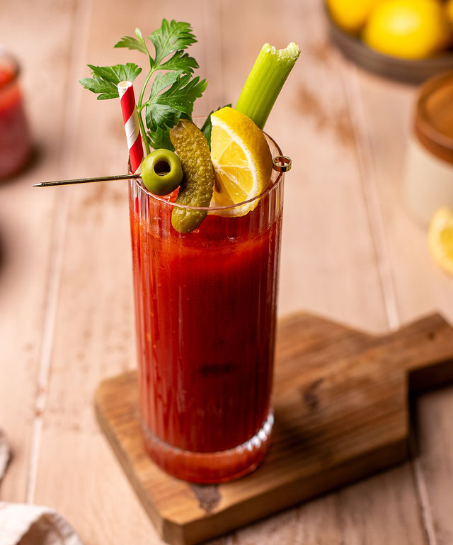 A bloody Mary mocktail dressed with pickles, sliced lemon, celery, and parsley.