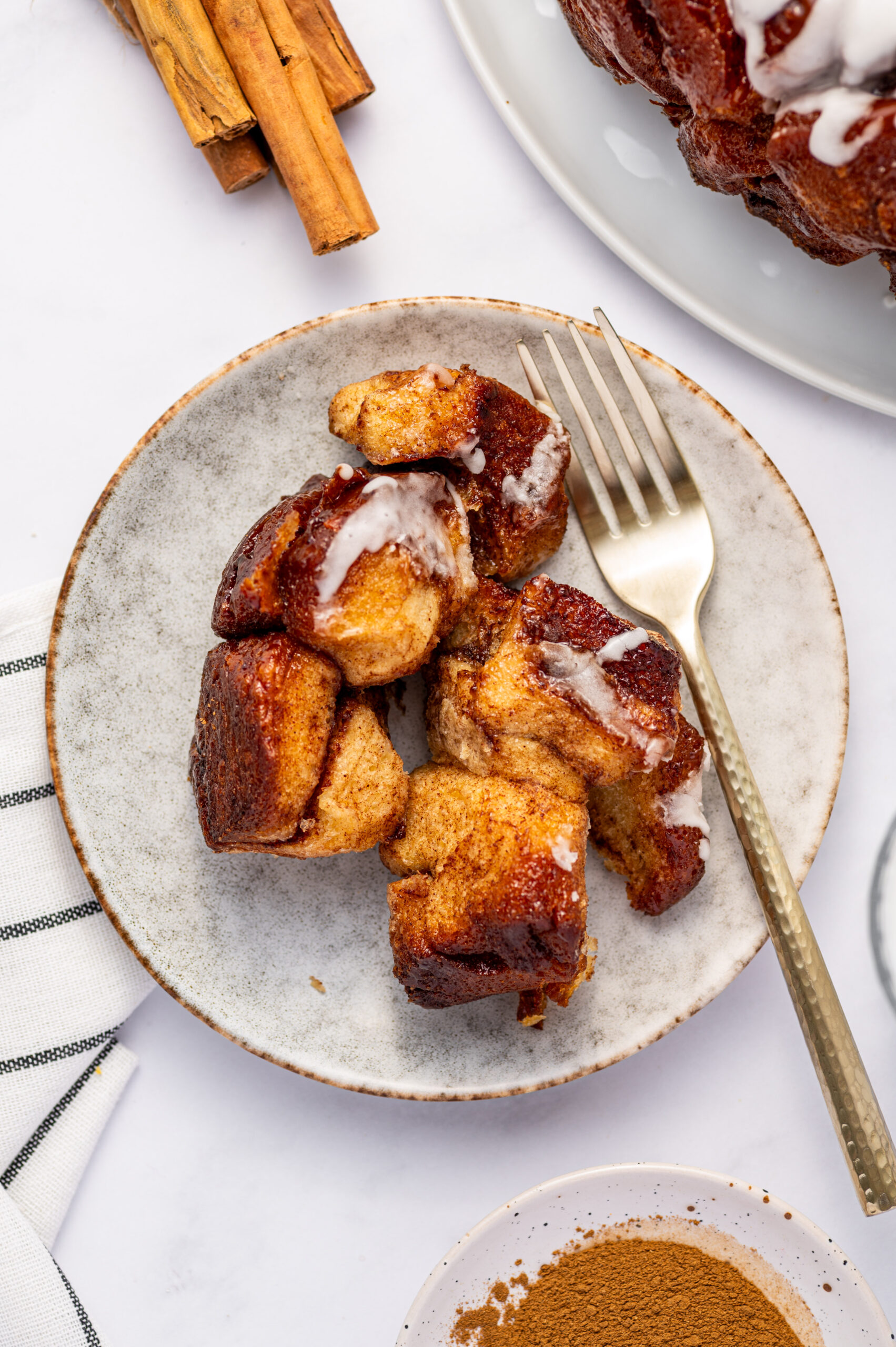 Pieces of cinnamon roll monkey bread on a plate with a fork.