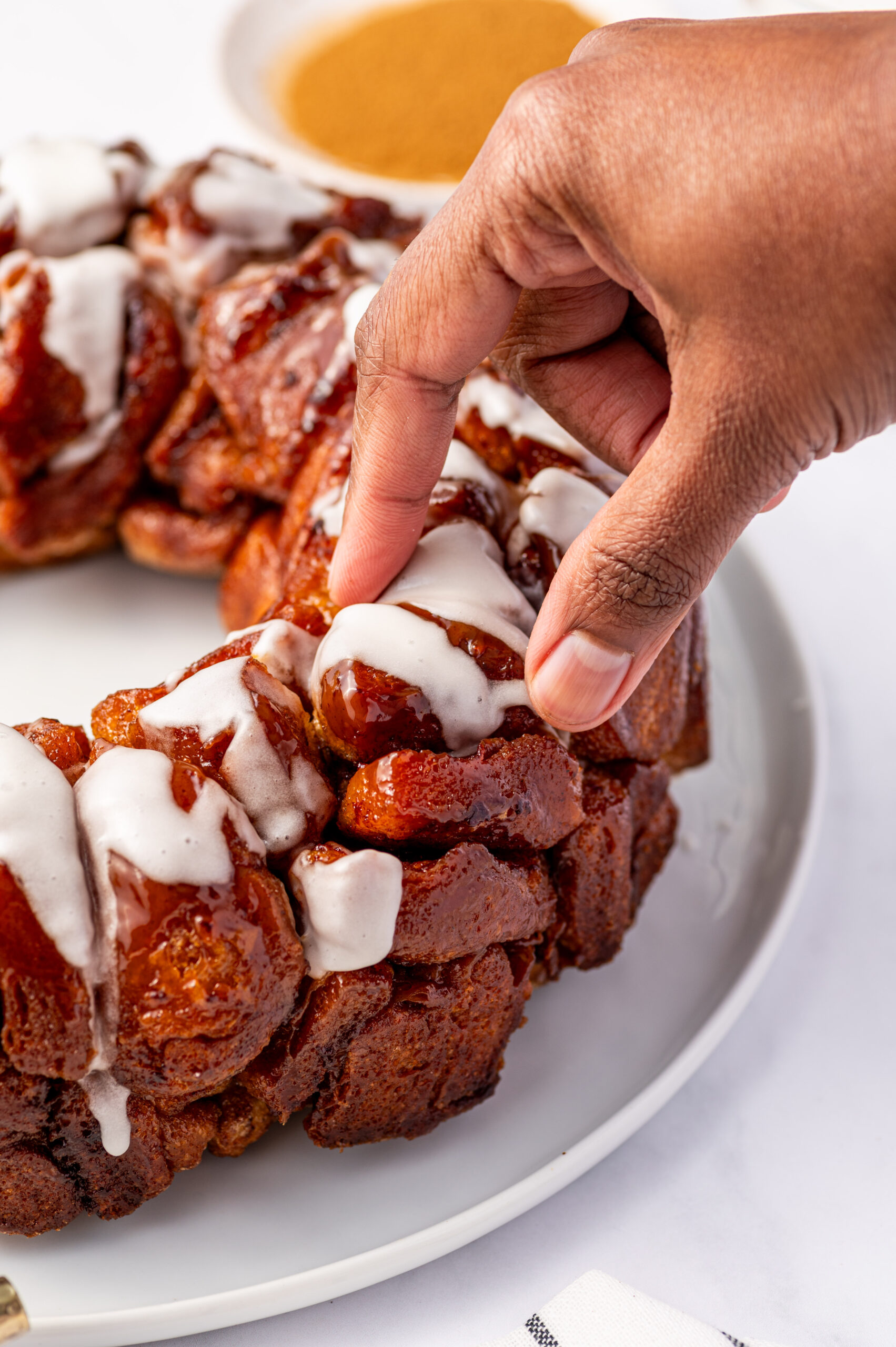 Grabbing a piece of cinnamon roll monkey bread drizzled with icing.