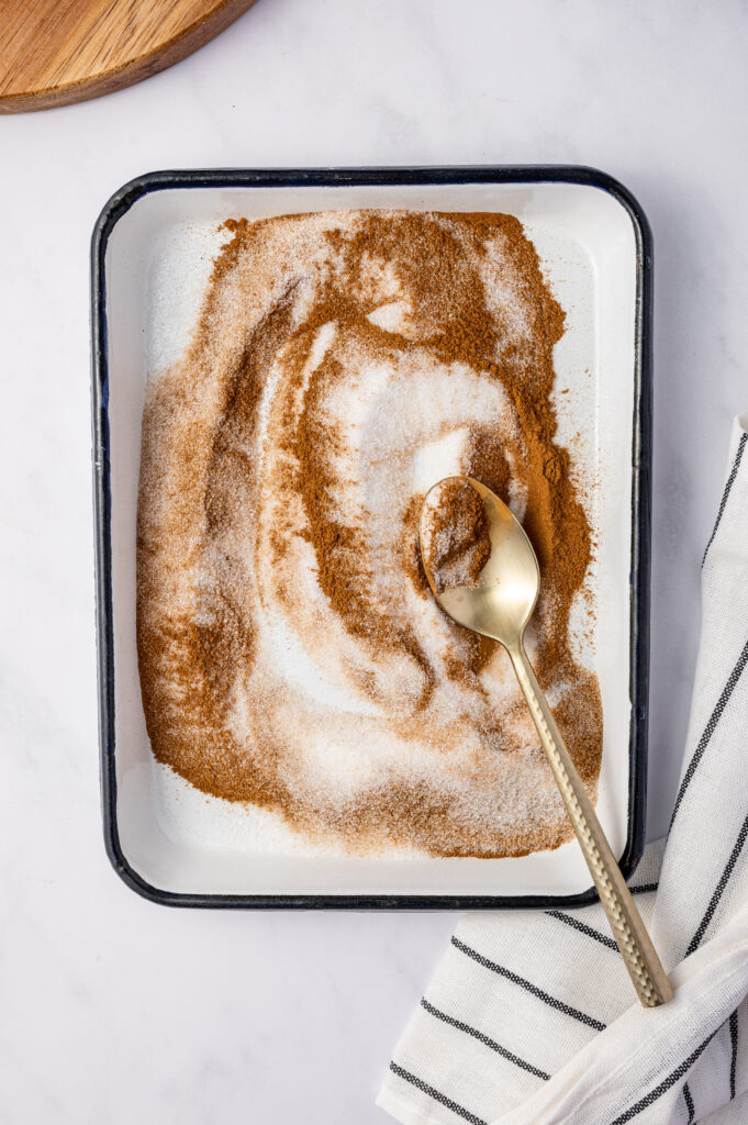Mixing cinnamon sugar in a shallow dish.