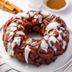 Gooey cinnamon roll monkey bread with icing over a white plate.