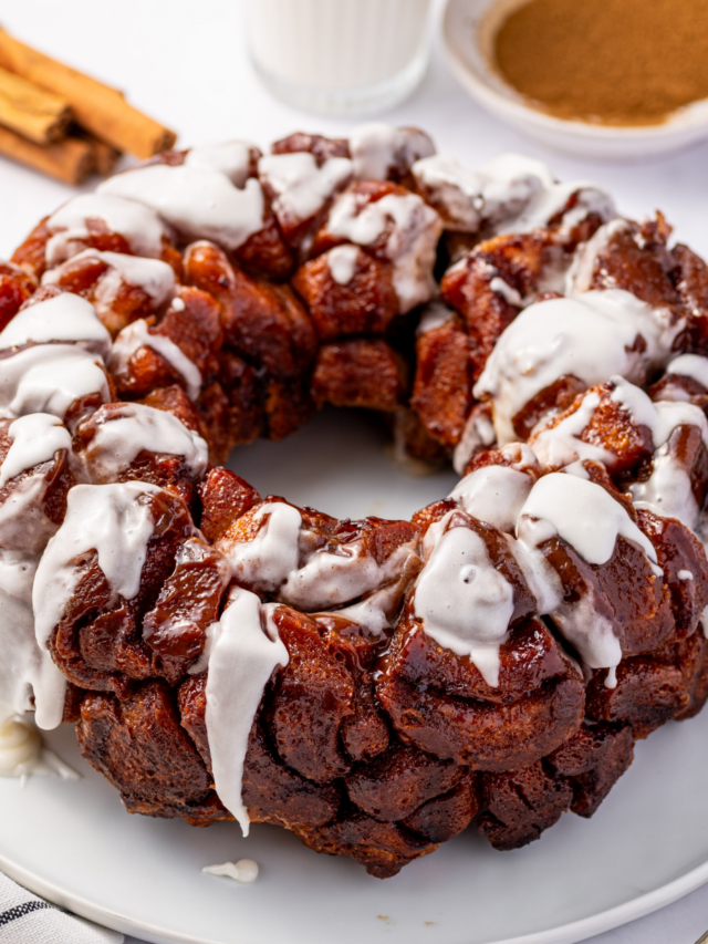 Gooey cinnamon roll monkey bread with icing over a white plate.