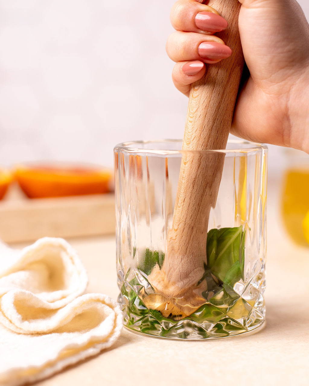 Muddling basil and honey simple syrup in a glass.