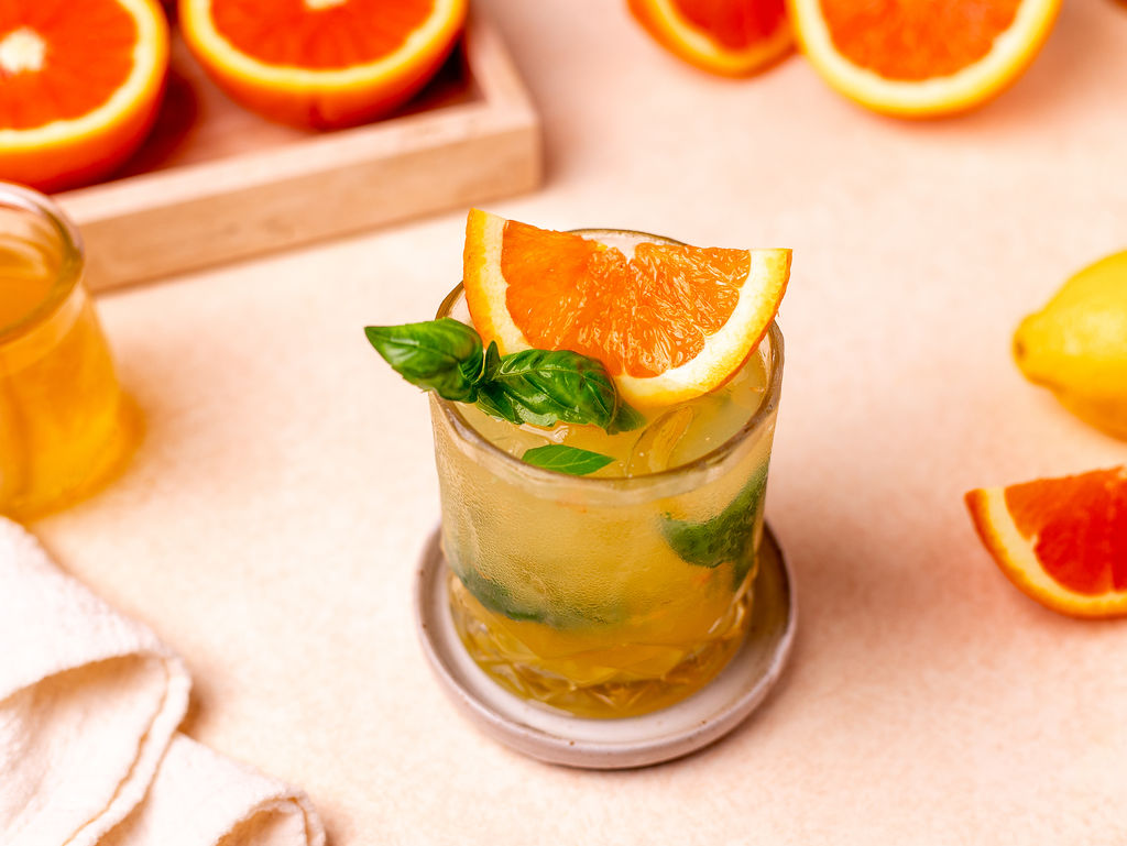 Citrus basil smash in a glass garnished with sliced orange and basil.
