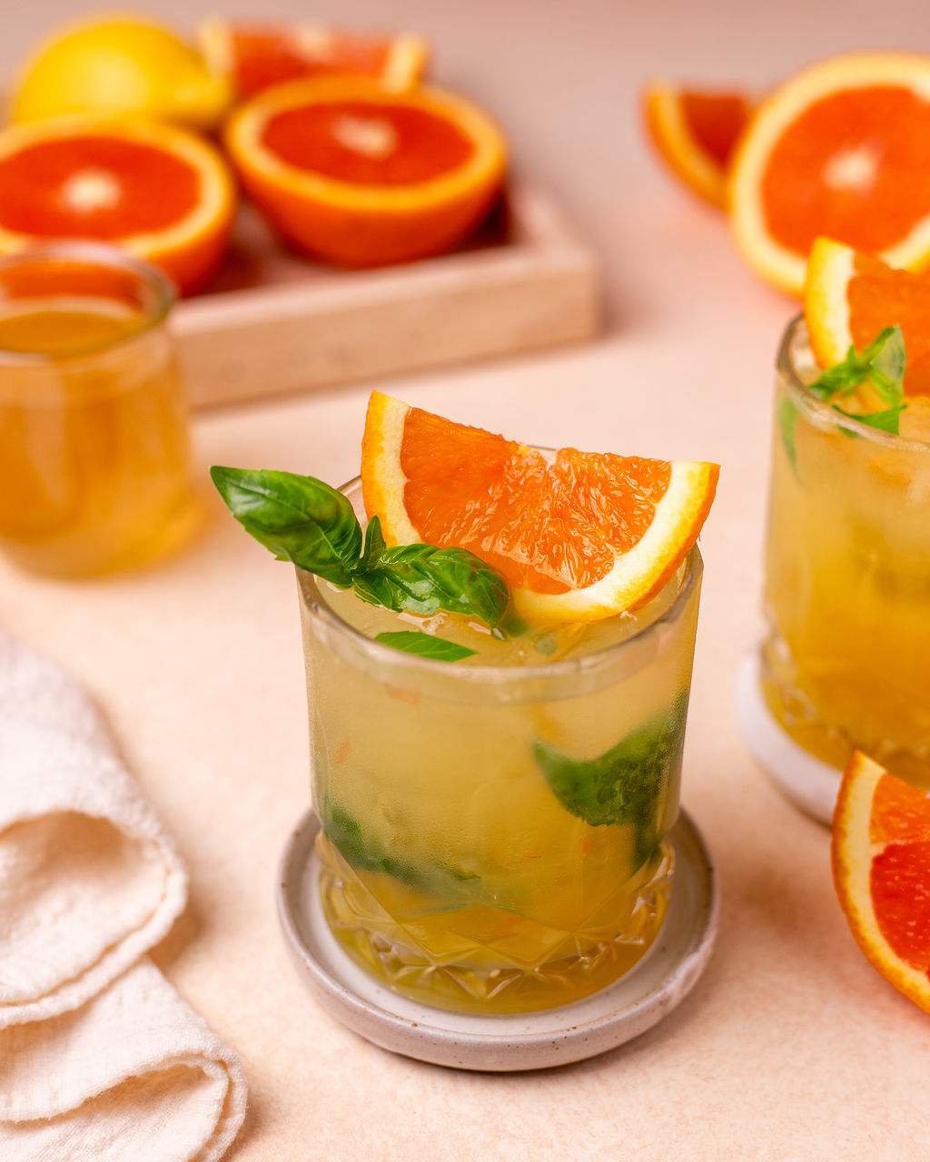 A glass of citrus basil smash with sliced orange and basil as a garnish.