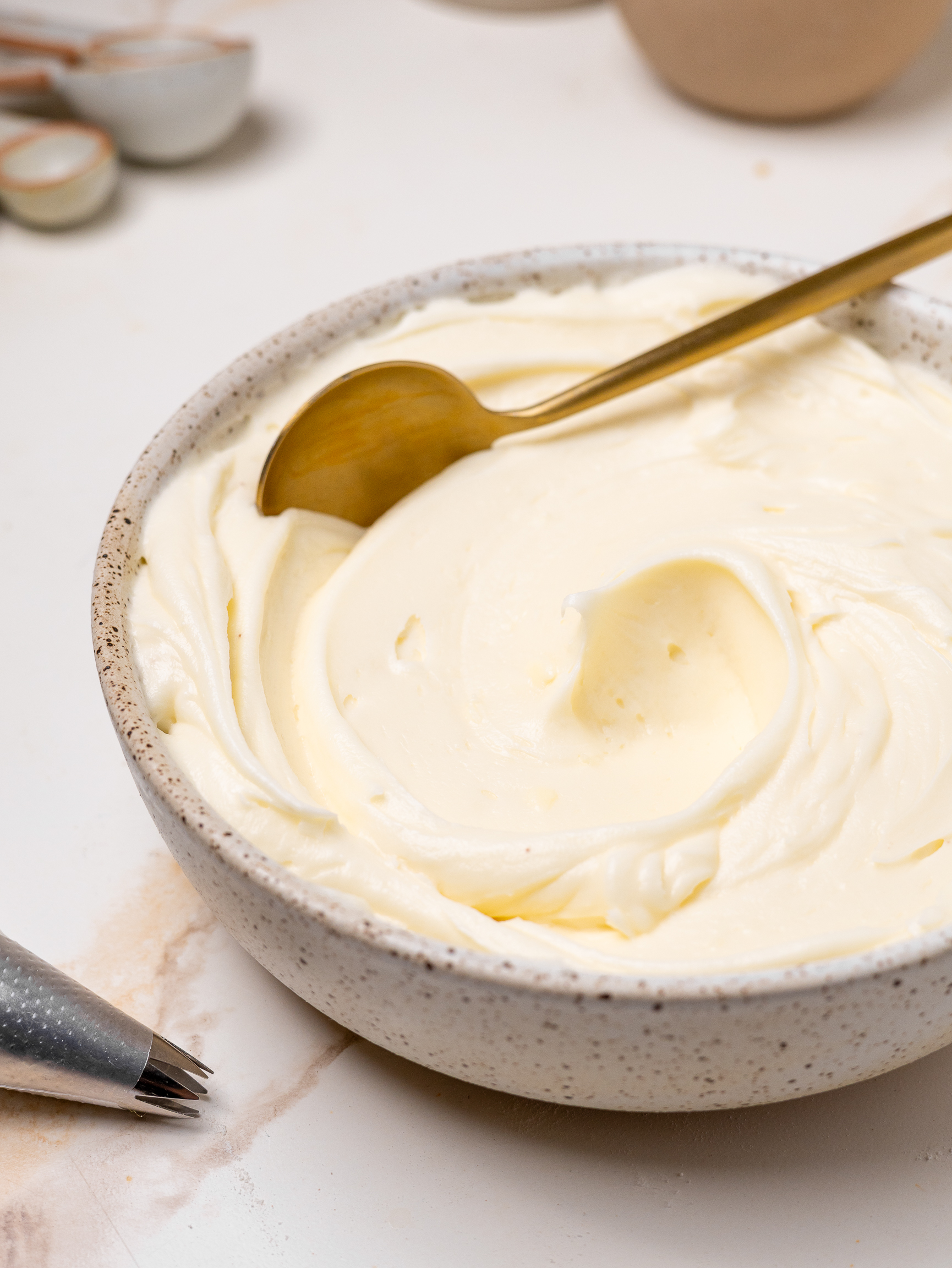 A glass bowl filled with smooth vanilla cake batter being whisked by a metal balloon whisk, showing its light and creamy texture.