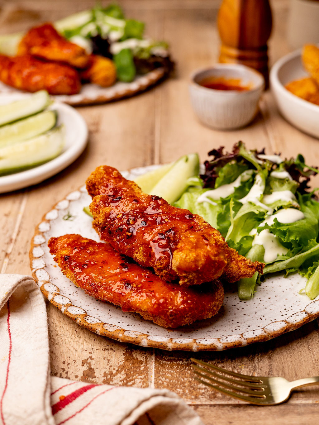 Air fryer hot honey chicken tenders on a plate with a side salad and pickles.