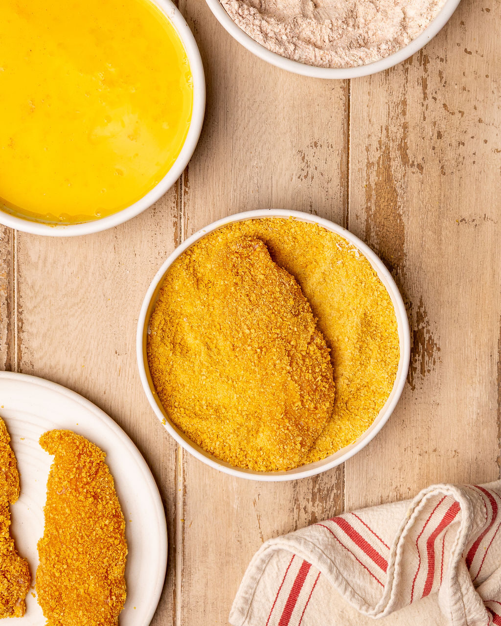 Dredging chicken tenders in a crushed cornflake breading.