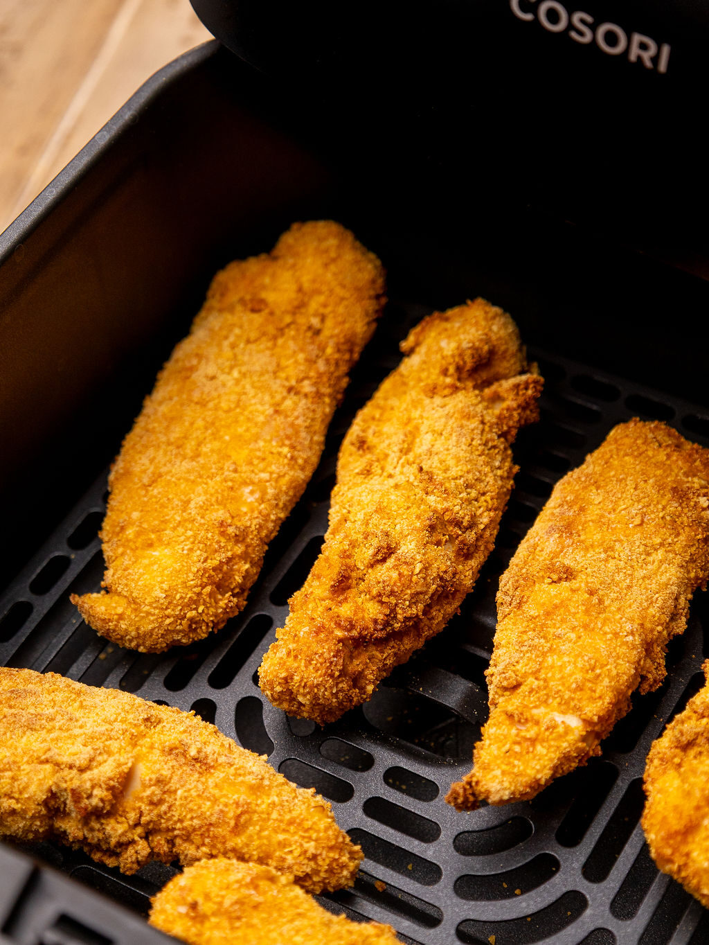 Cooked and breaded chicken tenders in an air fryer basket.