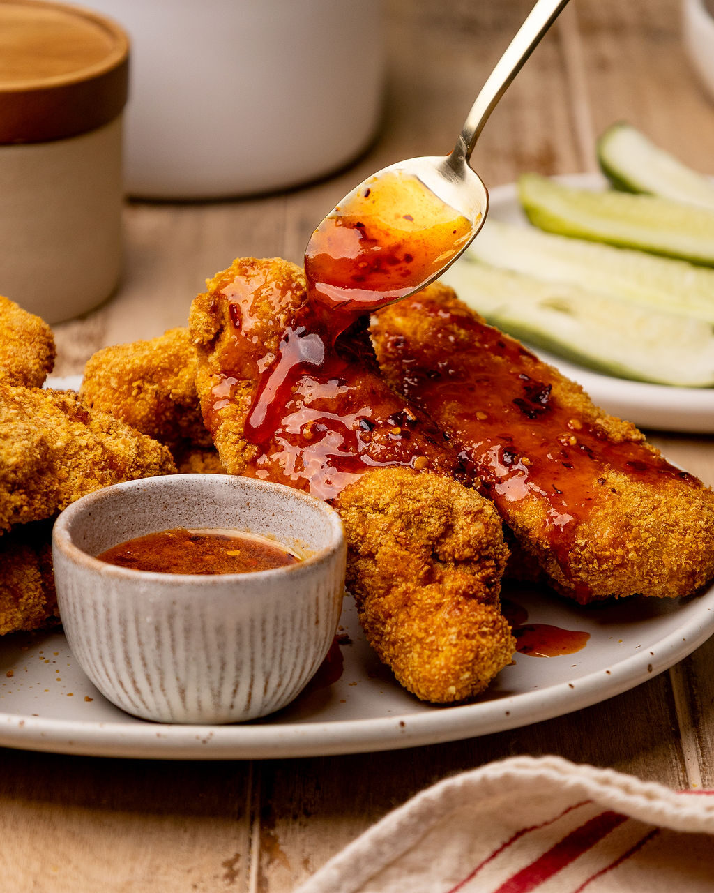 Spooning on hot honey sauce onto breaded chicken tenders.