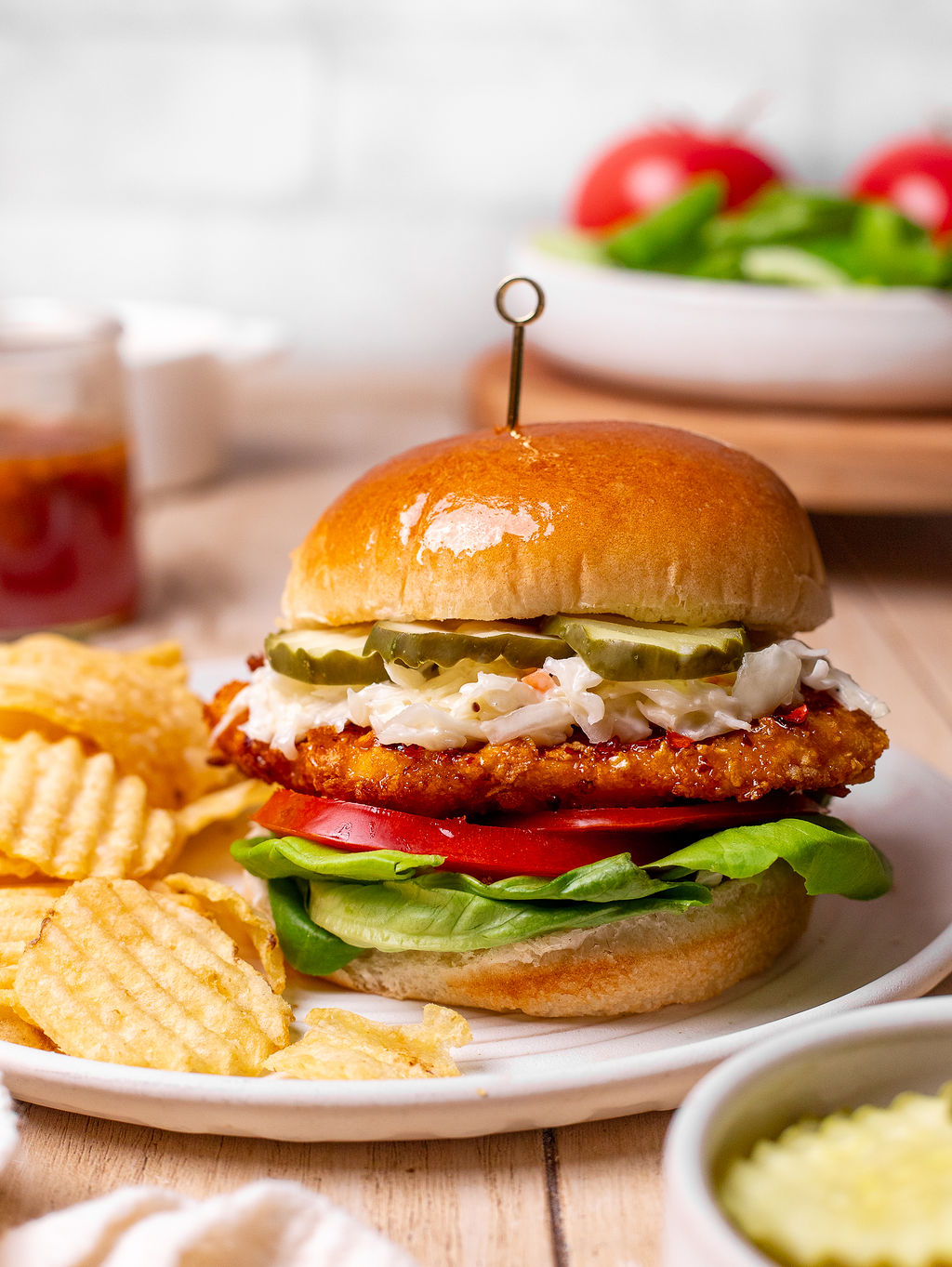 A hot honey chicken sandwich with a side of potato chips.