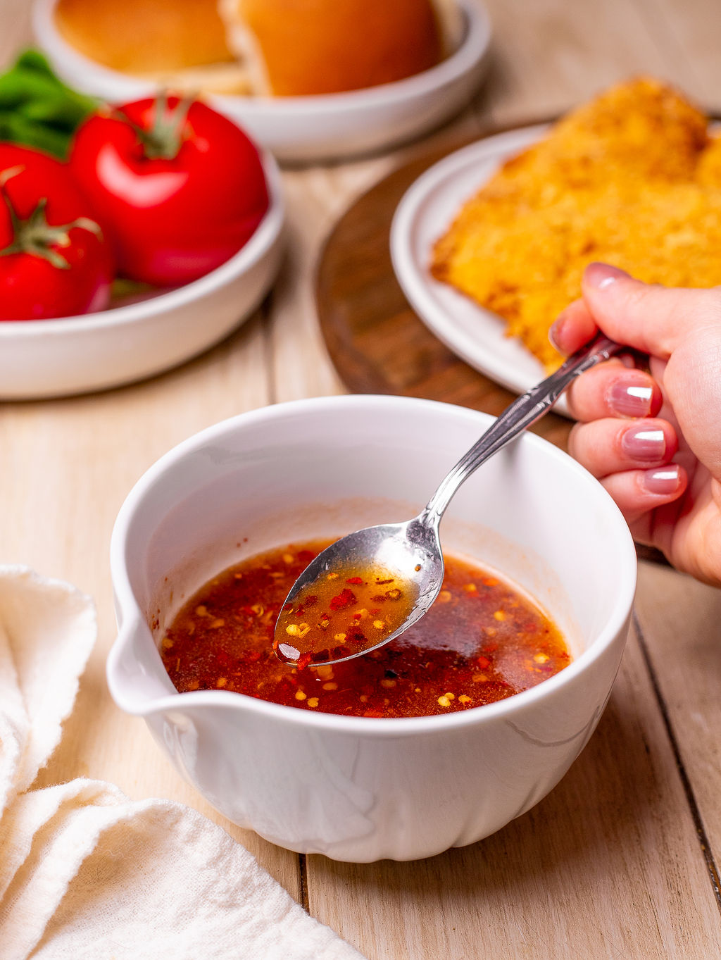 Hot honey sauce in a white bowl with a spoon.