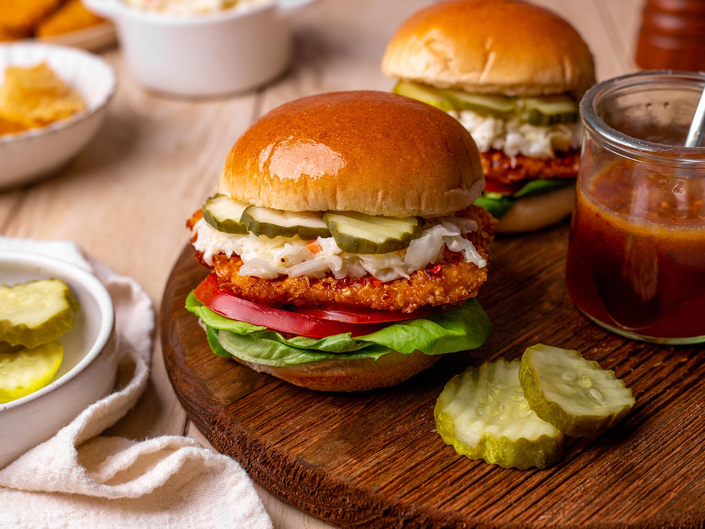 Air fryer hot honey chicken sandwiches on a wooden serving platter.