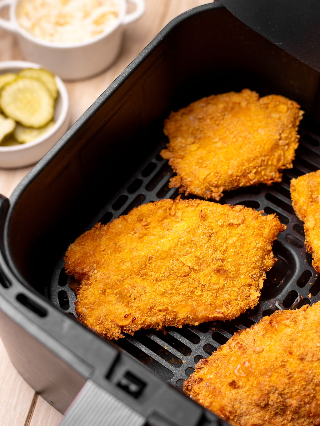 Cooked breaded chicken cutlets in an air fryer basket.