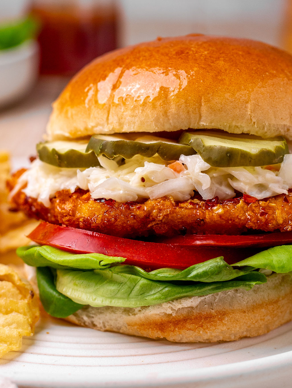 Close-up of a hot honey chicken sandwich layered with coleslaw, and sliced pickles.