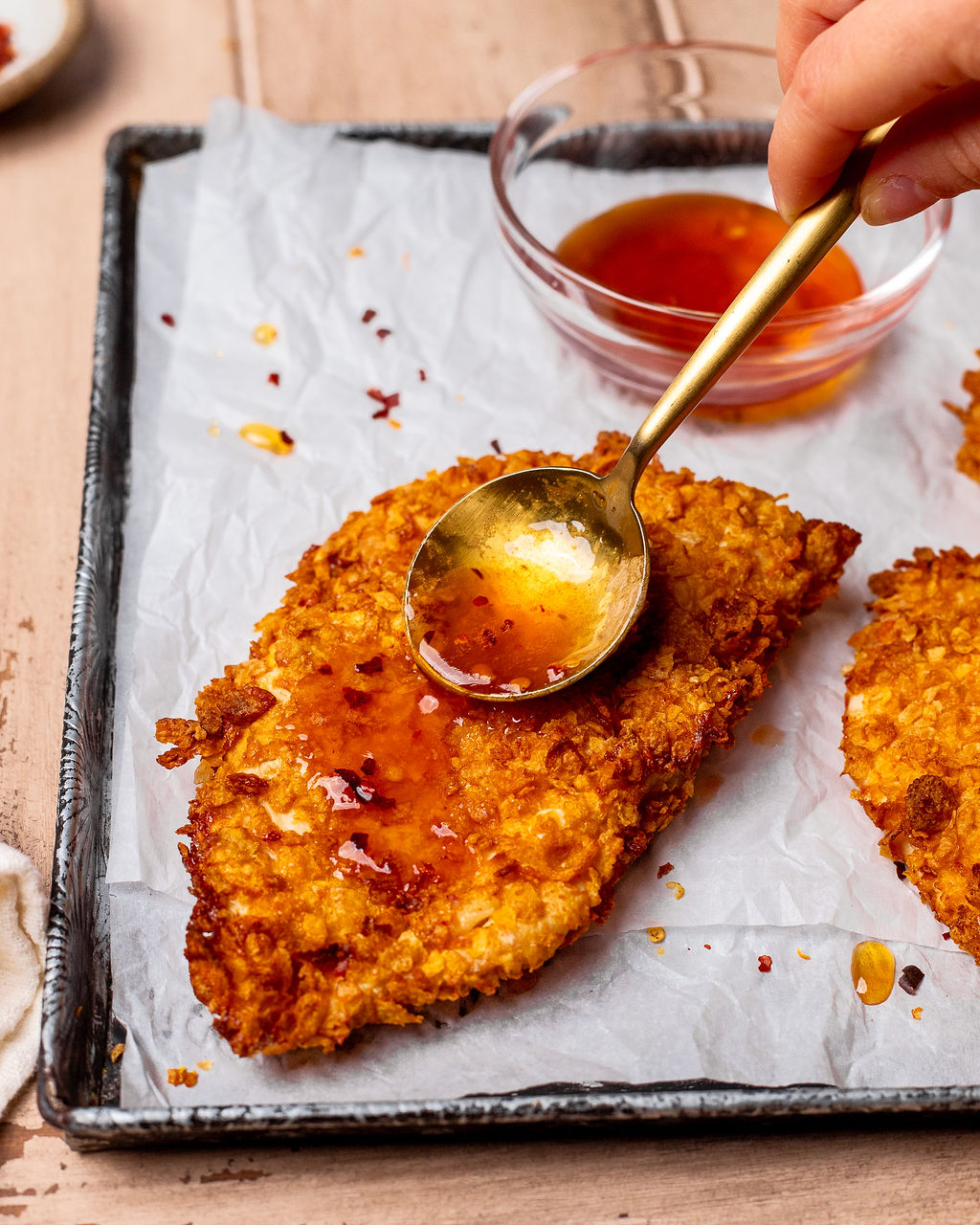 Spooning hot honey sauce onto crispy chicken filet.
