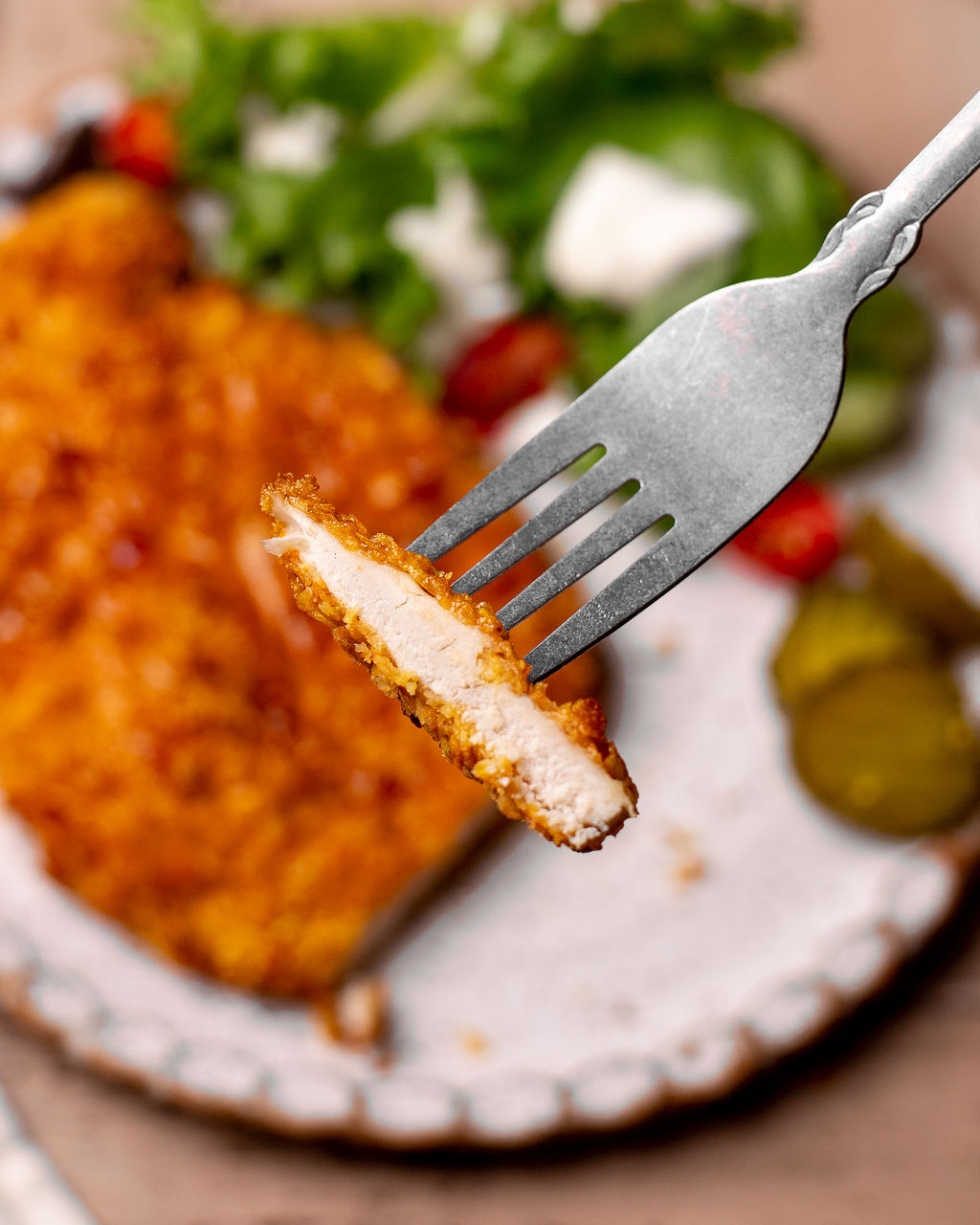 A forkful of hot honey chicken hovering over a plate.