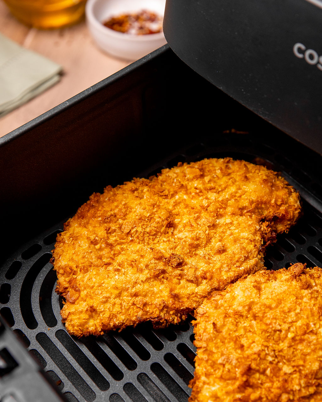 Freshly cooked crispy chicken breast in an air fryer basket.