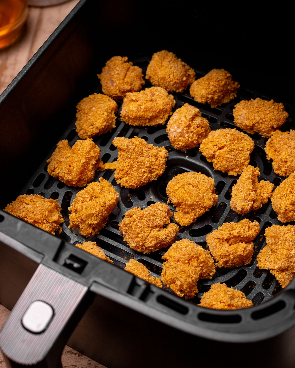 Freshly air fried chicken bites in an air fryer basket.