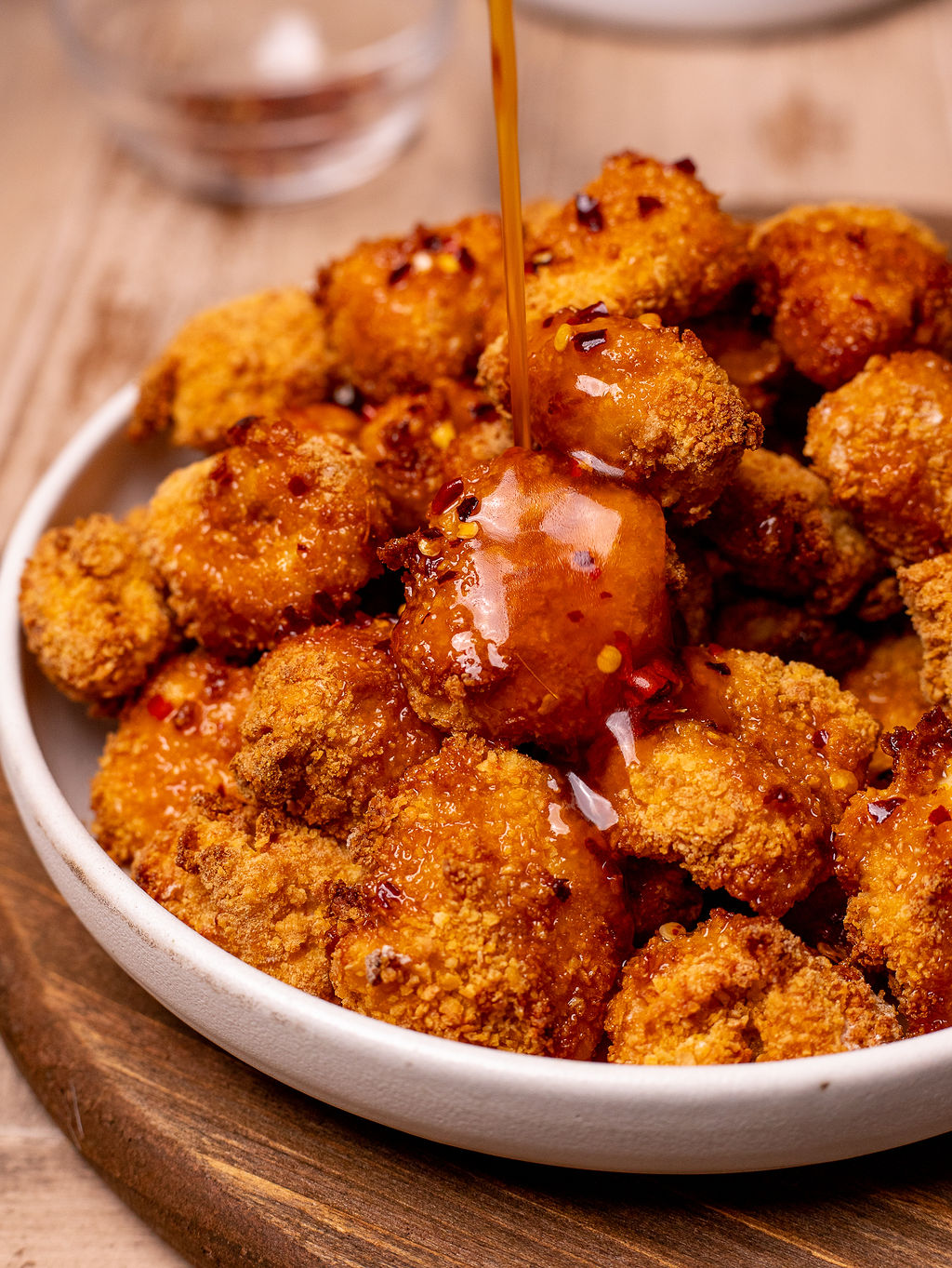 Close-up of hot honey sauce pouring on top of crispy air fried chicken.