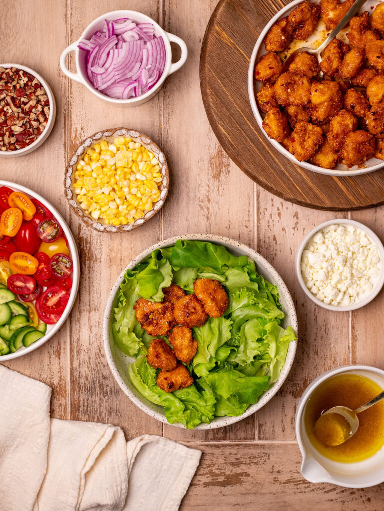 Assembling your hot honey chicken summer salad.