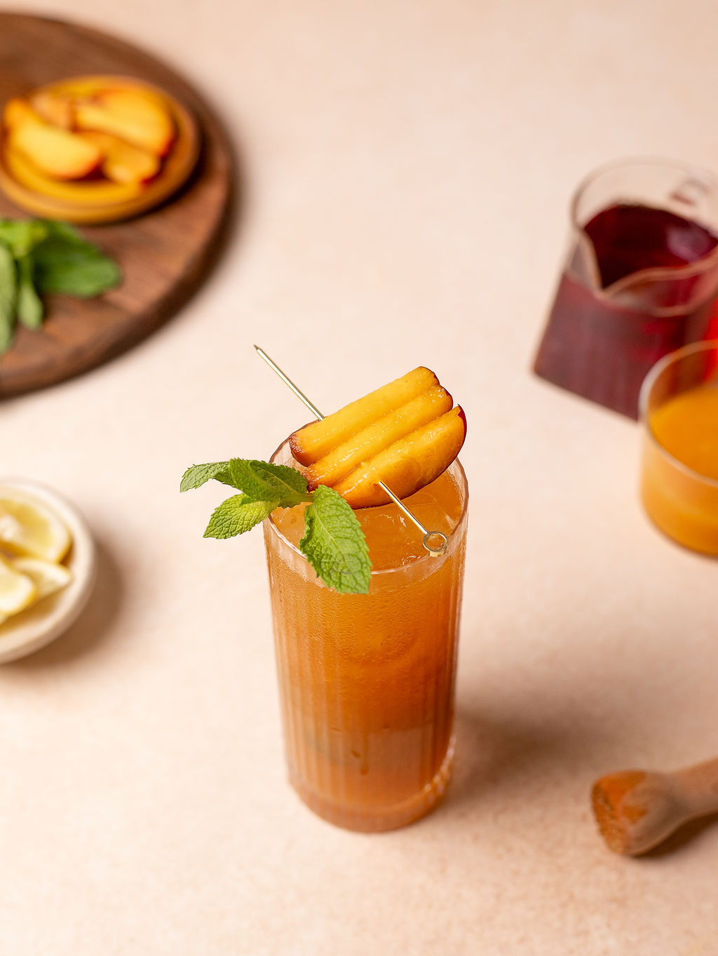 Aerial view of peach and mint iced tea in a tall glass with garnish.