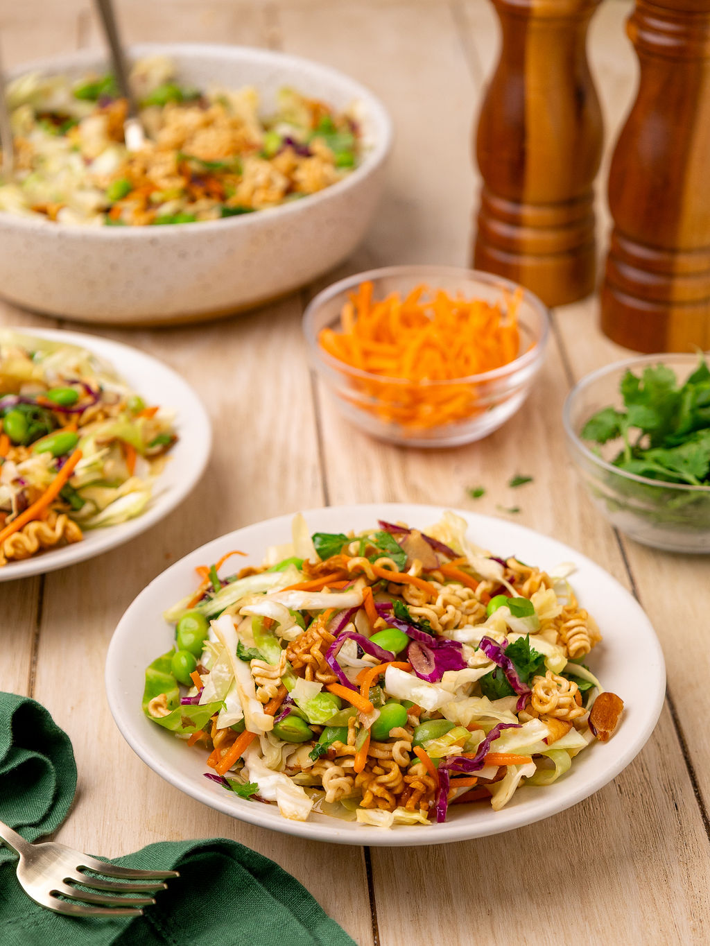 Ramen noodle salad in a bowl surrounded by ingredients.